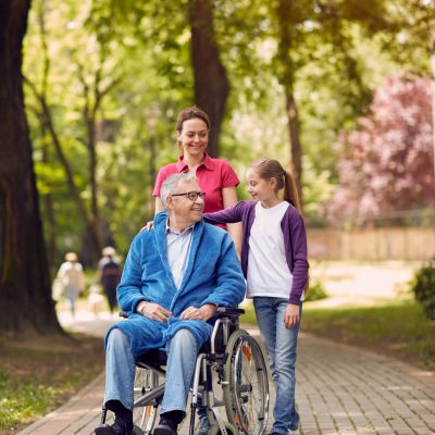 Disabled man in park spending time together with his daughter and granddaughter