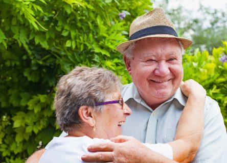 Cute elderly couple in love hugging and smiling outdoor in the green garden